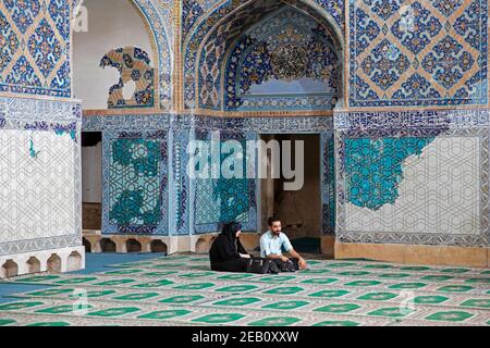 Giovane coppia musulmana seduta all'interno della Moschea Blu del XV secolo / Masjed-e Kabūd a Tabriz, Provincia dell'Azerbaigian Orientale, Iran Foto Stock