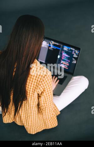 Giovane donna sviluppatore mobile scrive il codice del programma su un computer, lavoro del programmatore. Foto Stock