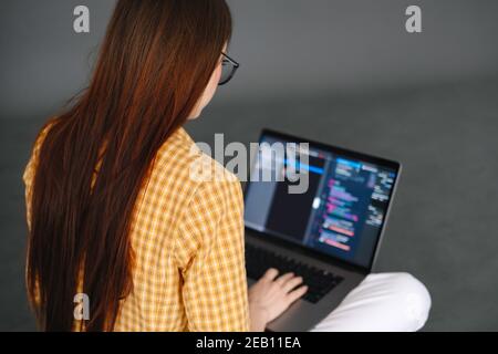 Giovane donna sviluppatore mobile scrive il codice del programma su un computer, lavoro del programmatore. Foto Stock