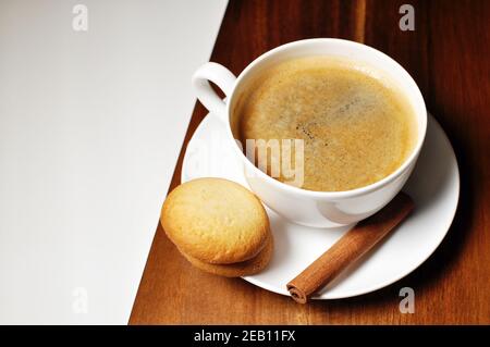 Tazza di caffè caldo con decorazione di cannella e biscotti su sfondo di legno marrone e bianco tavolo. Tabella superiore, testo dello spazio di copia. Foto Stock