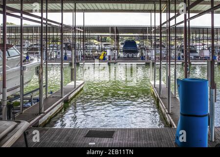 Barca vuota scivola in barca di lusso al lago con altri motoscafi ormeggiati in lontananza - alcuni su scaffali e roller floater pad in primo piano - pa blu Foto Stock