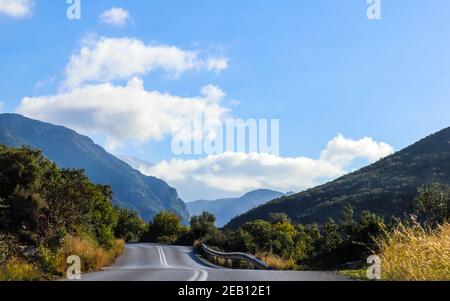 Curva di tornio su strada di montagna con nuvole e nebbia in lo sfondo Foto Stock