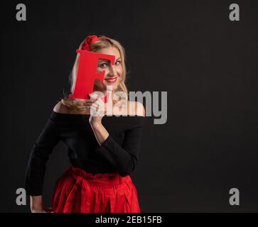 Una ragazza tiene le lettere della parola AMORE felice, cuore di San Valentino, cuori di nozze sul pavimento. Forma. Emozioni per sempre, gioia in una ragazza vestito rosso, bar Foto Stock