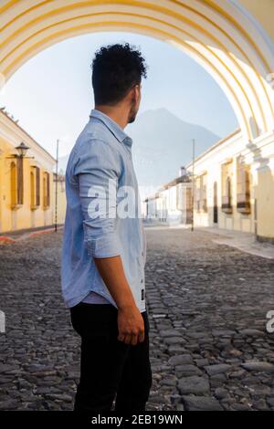 Giovane ispanico che si trova sotto l'Arco di Santa Catalina In Antigua Guatemala - turistico su viale importante di coloniale Città del Guatemala con la Wa Foto Stock