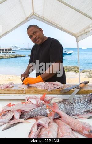 Uomo che vende pesce al mercato del pesce, nave da crociera & Blue Caribbean Sea George Town, Isole Cayman. Red & White Snapper, Street Market, nave da crociera. Foto Stock