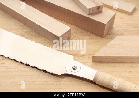 Gruppo di materiale di legno assortito e una sega a mano giapponese. Legno di carpenteria, materiale tagliato o legno concetto. Primo piano Foto Stock