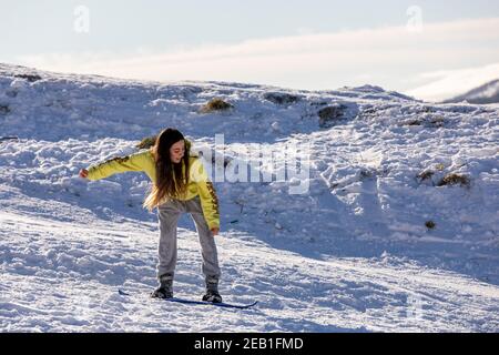 Una ragazza che impara a snowboard vicino Salisbury Crags Foto Stock