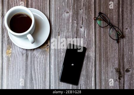 Un telefono cellulare o un telefono cellulare posato su un legno Tabella con l'app JD aperta sullo schermo accanto a. un caffè Foto Stock
