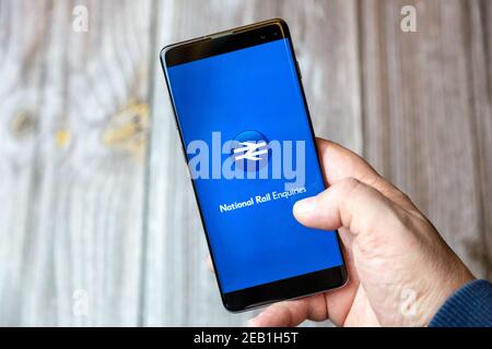 Un telefono cellulare o un telefono cellulare tenuto da un Mano con l'app National Rail Inquiries aperta sullo schermo Foto Stock