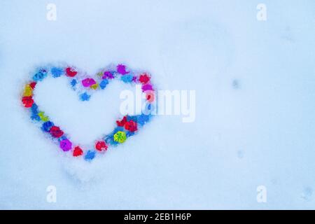 Cuore fatto di cristalli multicolore sulla neve Foto Stock