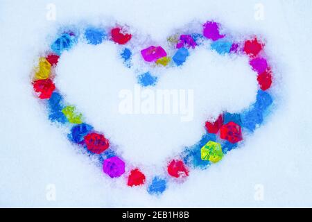 Cuore fatto di cristalli multicolore su fondo nevoso Foto Stock