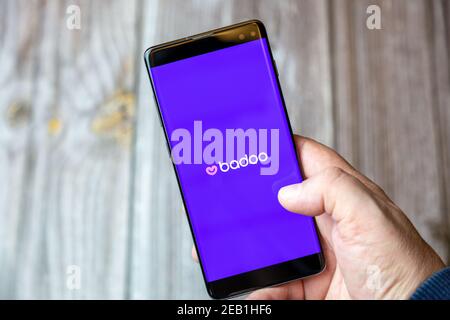 Un telefono cellulare o un telefono cellulare tenuto da un mano con l'applicazione online di datazione badoo aperta sullo schermo Foto Stock