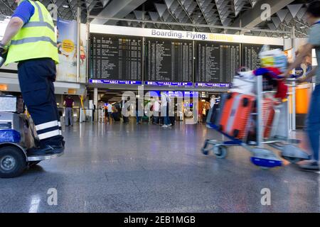 air passengers with luggage checking  flights on concourse at Frankfurt airport, Germany Foto Stock