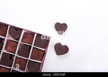 Scatola con dolci a forma di cuore al cioccolato su sfondo bianco. Concetto di San Valentino. Spazio di copia. Foto Stock