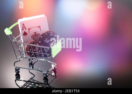 Casino chip e carte per giocare il casinò in un carrello su uno sfondo con bokeh. Gioco d'azzardo online. Dipendenza. Foto Stock