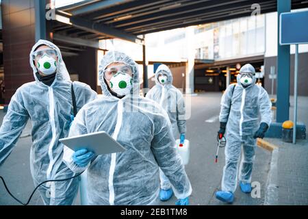 Operatori sanitari che indossano tute nocciole che lavorano insieme durante un focolaio in città Foto Stock