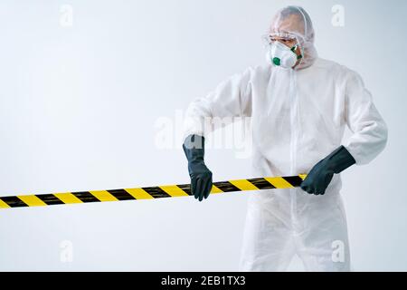 Operatore sanitario che si allontana dall'area con nastro protettivo durante un focolaio di virus Foto Stock