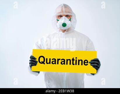 Operatore sanitario in tuta protettiva e maschera medica contiene carta Con il testo 'quarantena' Foto Stock