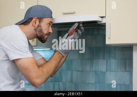 Veloce e professionale. Un giovane uomo a mano che guarda messo a fuoco mentre fissa un estrattore da cucina con un cacciavite all'interno Foto Stock