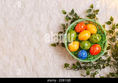 Carta di Pasqua. Composizione piatta con uova di pasqua in un cesto su sfondo bianco. Foto Stock