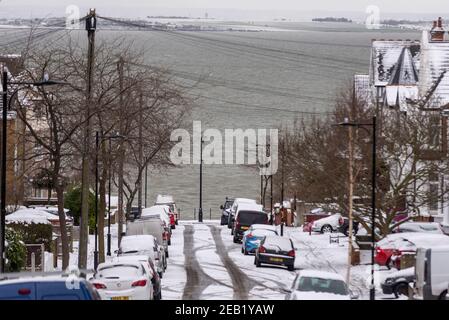 Strada che scende al Tamigi estuario a Southend sul mare, Essex, Regno Unito, con la neve da Storm Darcy. Guardando verso Kent. Strada ghiacciata. Wintry mare Foto Stock