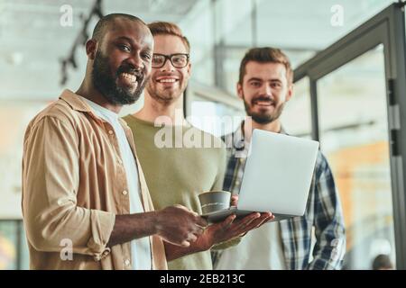 Tre giovani uomini di lavoro multirazziali che posano per la macchina fotografica Foto Stock