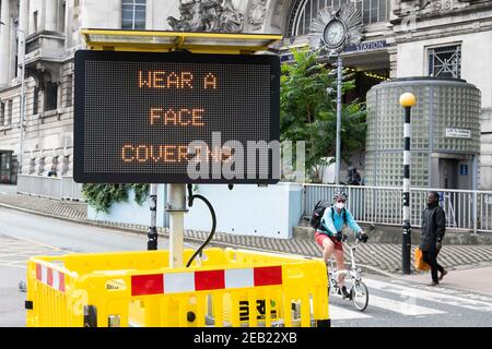 "Indossare una maschera facciale" è visualizzato su un cartello elettronico fuori dalla stazione di Waterloo, Londra, in quanto l'uso obbligatorio della maschera è introdotto durante la pandemia di Covid-19, Regno Unito. Foto Stock