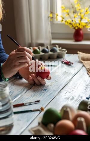 Pittura e colorazione uovo per la vacanza di Pasqua. Donna che decora le uova di pasqua per le feste religiose tradizionali. Arte e artigianato concetto con le mani femminili Foto Stock