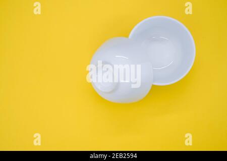 Primo piano di due ciotole bianche vuote su sfondo giallo con spazio per il testo Foto Stock