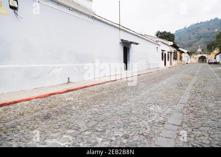 Strada coloniale nel centro della città di Antigua Guatemala - strada con strada in pietra e vecchie case - via vuota Foto Stock