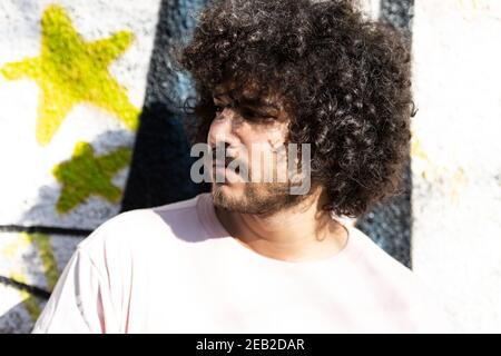 Ritratto di un giovane uomo Afro capelli in posa a Graffiti Parete esterna Foto Stock