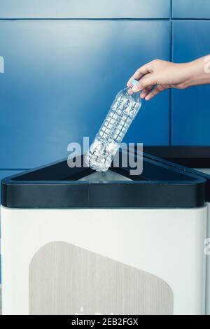 Salva mondo verde e cura il concetto di Terra, primo piano Donna mano sta gettando bottiglia di plastica nel cestino spazzatura mentre si separa per riutilizzo e riciclaggio. Foto Stock