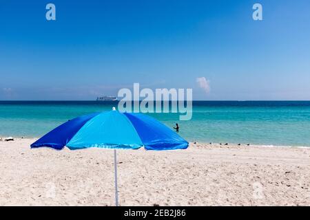 Un ombrellone blu incorniciato contro le acque azzurre dell'Atlantico al largo di South Beach, Miami Beach, Florida Foto Stock