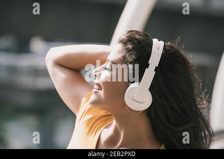 Giovane donna ispanica che indossa le cuffie per ascoltare la musica occhi chiusi Foto Stock