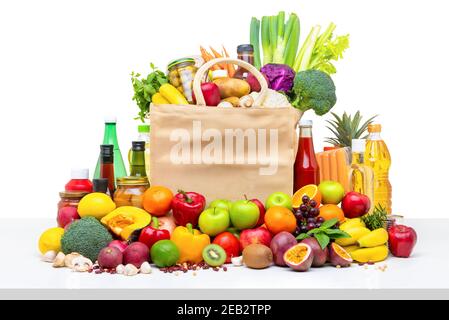 Shopping bag piena di varietà di frutta fresca biologica colorata e verdure con ingredienti assortiti sulla parte superiore di un tavolo in studio isolato bianco retro Foto Stock