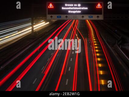 Pang, Germania. 12 Feb 2021. Un cartello con la scritta "confine con l'Austria - controlli sanitari - rischio di ingorghi" si trova sull'Autobahn 8, vicino allo svincolo di Inntaldreieck. Nella lotta contro la variante della corona sudafricana in espansione, lo Stato austriaco del Tirolo ha messo in vigore nuove restrizioni all’uscita ieri sera. Credit: Peter Kneffel/dpa/Alamy Live News Foto Stock