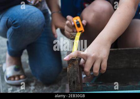 Il bambino sta riparando legno con una matita e nastro misura Foto Stock