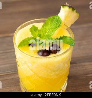 Primo piano di una rinfrescante bevanda estiva all'ananas tropicale su sfondo tavolo di legno Foto Stock