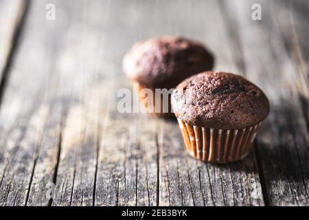 Muffin al cioccolato. Dolci cupcake scuri su tavolo di legno. Foto Stock