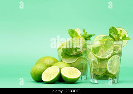 Rinfrescanti cocktail Mojito nei bicchieri a fette fresche lime e foglie di menta piperita su sfondo verde Foto Stock