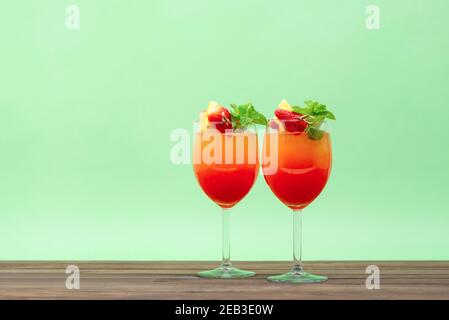 Rinfrescanti e colorati cocktail di frutta all'alba su un tavolo in legno sfondo verde pastello Foto Stock