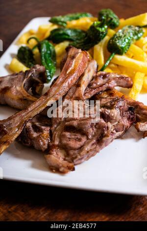 Costolette di agnello alla griglia. Carne servita con patatine fritte e peperoni. Immagine verticale Foto Stock