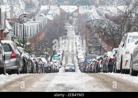 Londra, Regno Unito - 9 febbraio 2021 - un'auto che guida in salita su una strada coperta di neve a Crouch End, condizioni di guida avverse Foto Stock