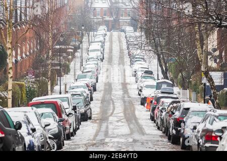 Londra, UK - 9 Febbraio, 2021 - lunga strada terrazzata con auto parcheggiate coperte di neve nell'area di Crouch End Foto Stock