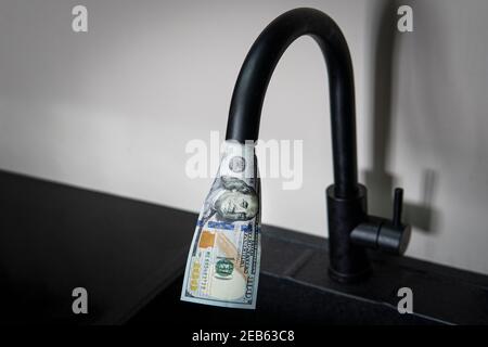 Tocca con i dollari che ne fuoriescono. Approvvigionamento di acqua costoso. Il concetto di aumentare il prezzo dei servizi pubblici per la popolazione. Caldo costoso Foto Stock