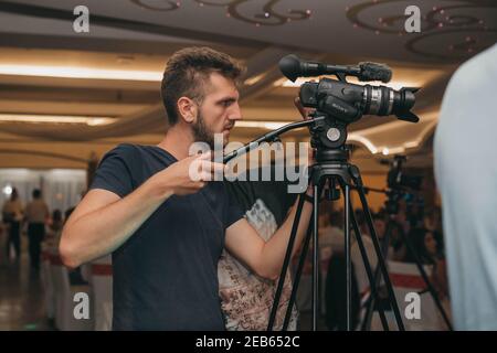 BRCKO, BOSNIA-ERZEGOVINA - 07 novembre 2019: Uomo che tiene il treppiede con la fotocamera Sony durante la festa di nozze Foto Stock