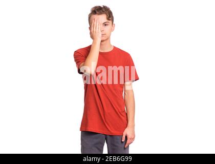 Triste bel ragazzo teen guarda con un occhio mentre copre l'altro occhio con la mano, isolato su sfondo bianco Foto Stock