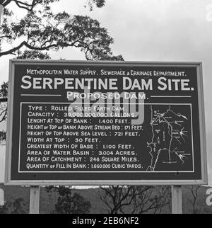 Un cartello che indica la posizione del sito della diga di Sepentine, Serpentine, Australia Occidentale, Australia c. 1958. La costruzione della diga fu completata nel 1961. Il serbatoio della diga viene utilizzato per immagazzinare l’acqua che viene rilasciata per alimentare l’acqua alla rete principale del tronco metropolitano. La diga di Serpentine è una delle 15 dighe (alcune delle quali sono state poi smantellate) costruite a Washington dagli anni venti – parte del sistema integrato di approvvigionamento idrico (IWSS), che fornisce acqua a oltre due milioni di persone a Perth, Mandurah e in altre regioni dell'Australia occidentale. Foto Stock