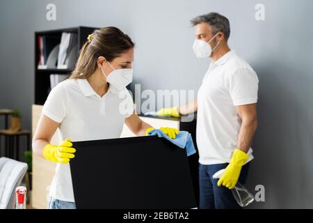 Janitor Service Woman Cleaning Monitor su scrivania in maschera facciale Foto Stock