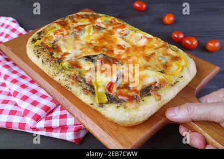 Preparare a mano deliziosa pizza veggie al pesto appena sfornata fatta in casa il tavolo Foto Stock